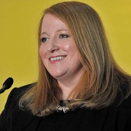 Alliance Party leader Naomi Long stands in front of a microphone.